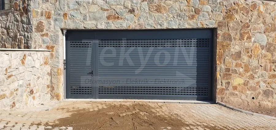 Taş duvarlı garaj girişinde antrasit motorlu kepenk – TekyöN Otomasyon